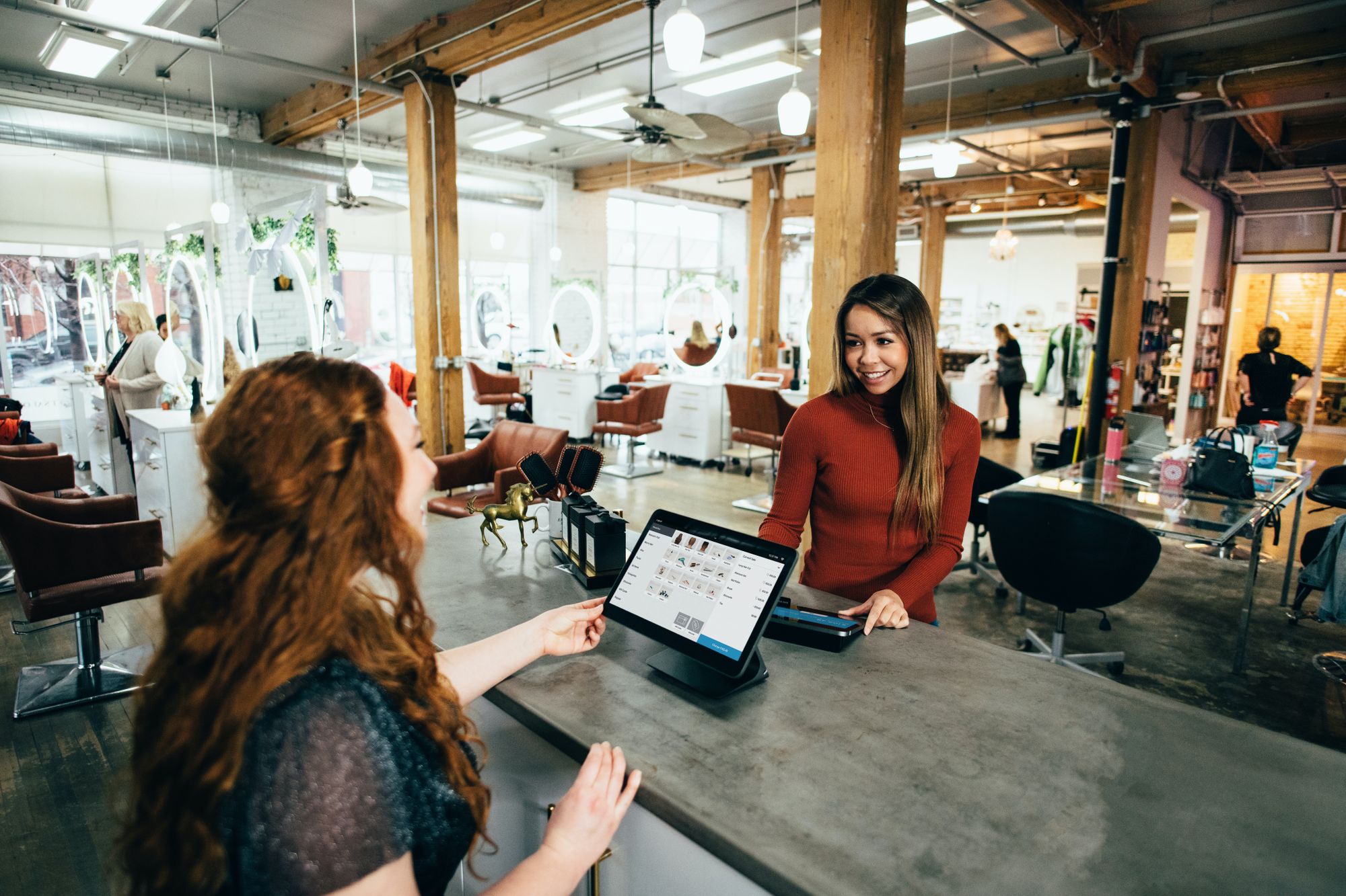 Woman being served by a woman by the counter in a hair salon